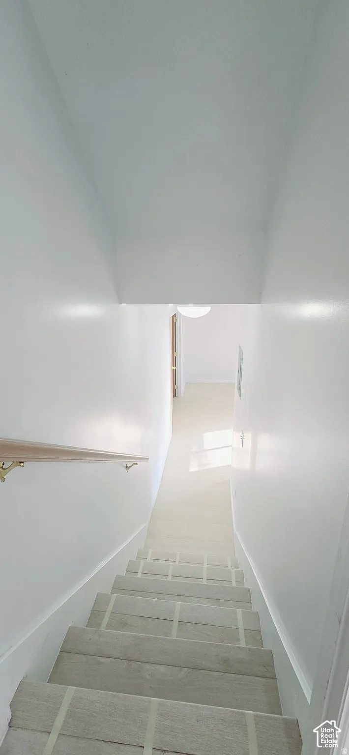 White-painted staircase with light wood-finish treads and a natural wood handrail featuring brass brackets