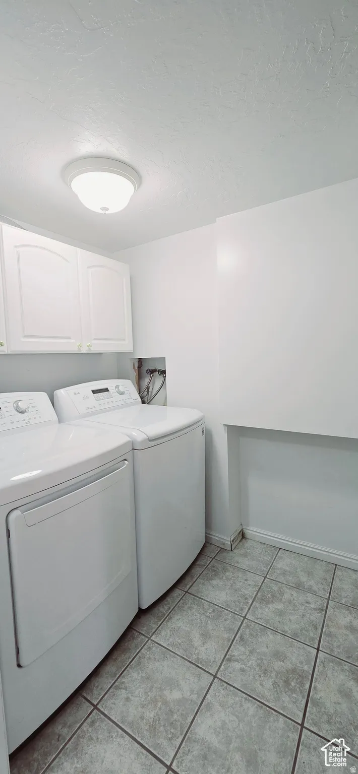 Dedicated laundry space featuring white cabinetry, a built-in wall shelf, and square tile flooring