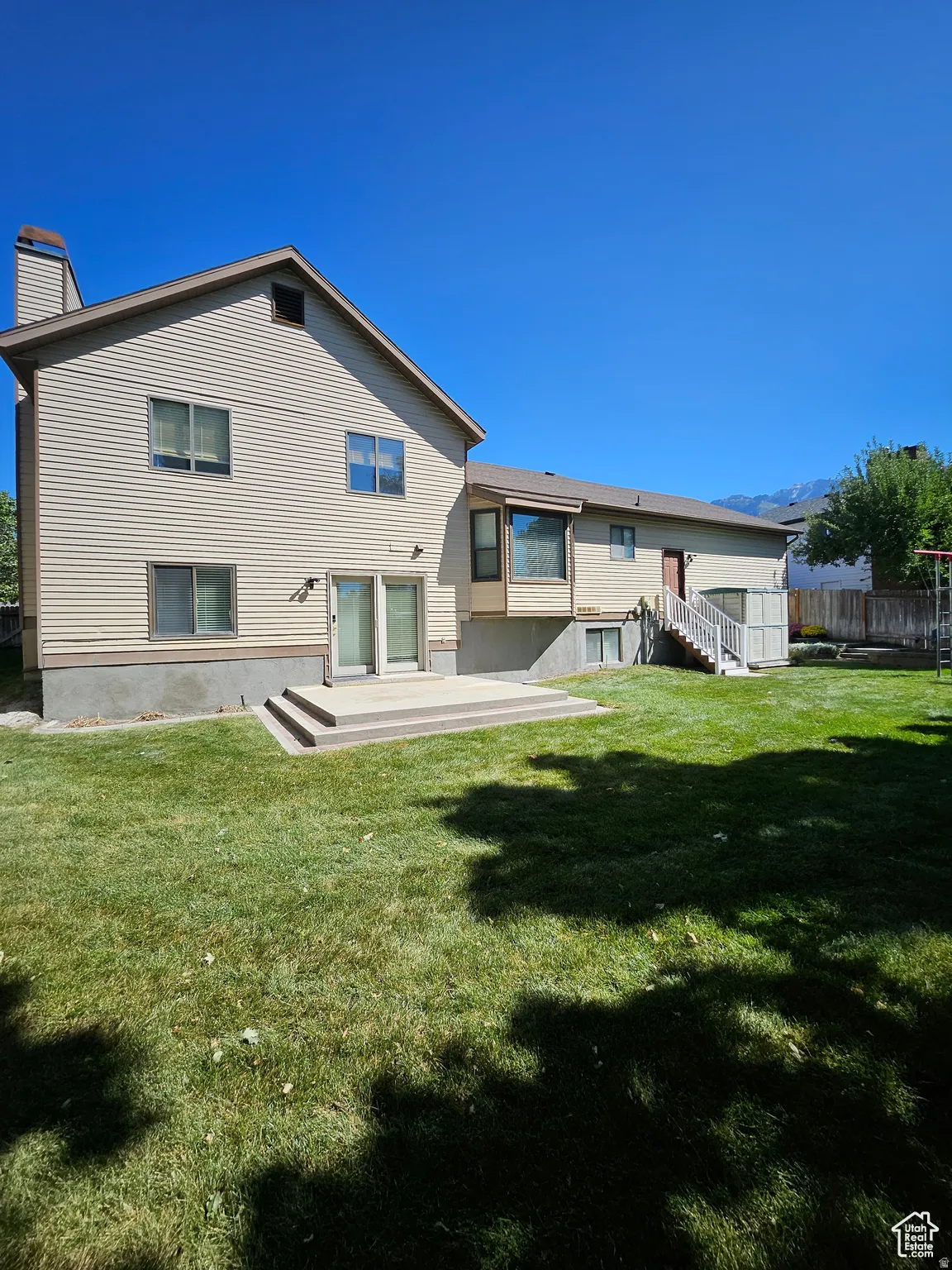 Expansive rear exterior featuring a concrete patio, sliding glass doors, and a bay window