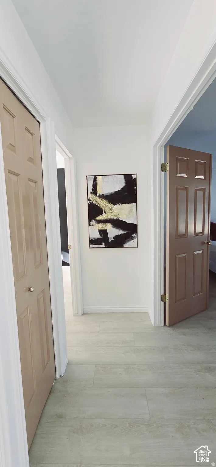 Hallway featuring wood-finish flooring and white baseboards