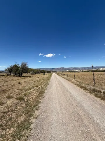 Gravel road extending through open land with distant mountains