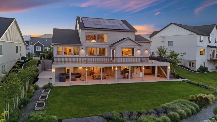 Rear exterior featuring a multi-level deck, ground-level patio, and a manicured lawn