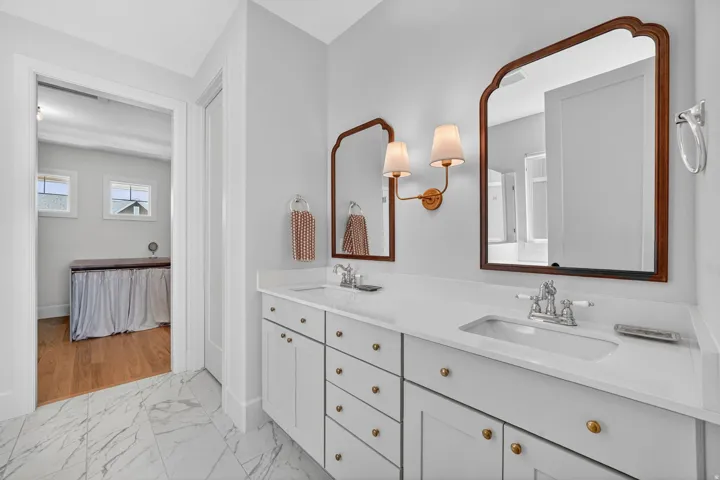 Dual vanity featuring white cabinetry, brass hardware, and a light-toned countertop