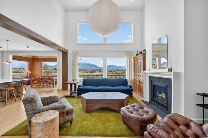 Vaulted ceiling living area with a fireplace and large windows showcasing mountain scenery