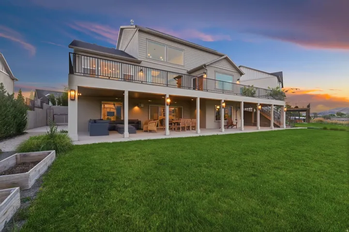 Expansive green lawn with a two-story residence featuring a large upper-level balcony with black railings