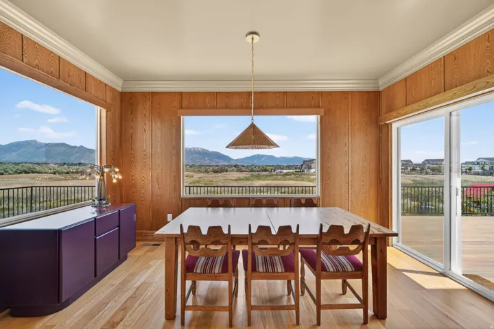 Dining space with wood-finish flooring, wood paneling, and wide crown molding
