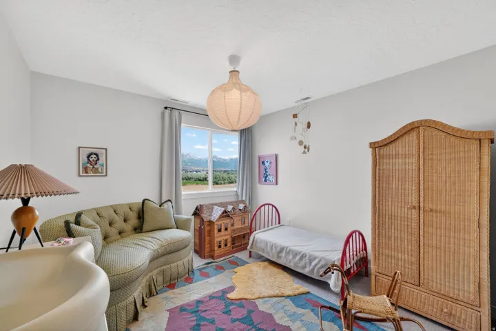 Light-filled room featuring a large window with mountain scenery, a unique pendant light fixture, and neutral wall tones