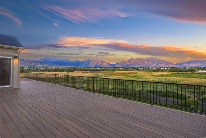 Expansive outdoor deck featuring wood-finish flooring, black metal railing, and direct access through a sliding glass door