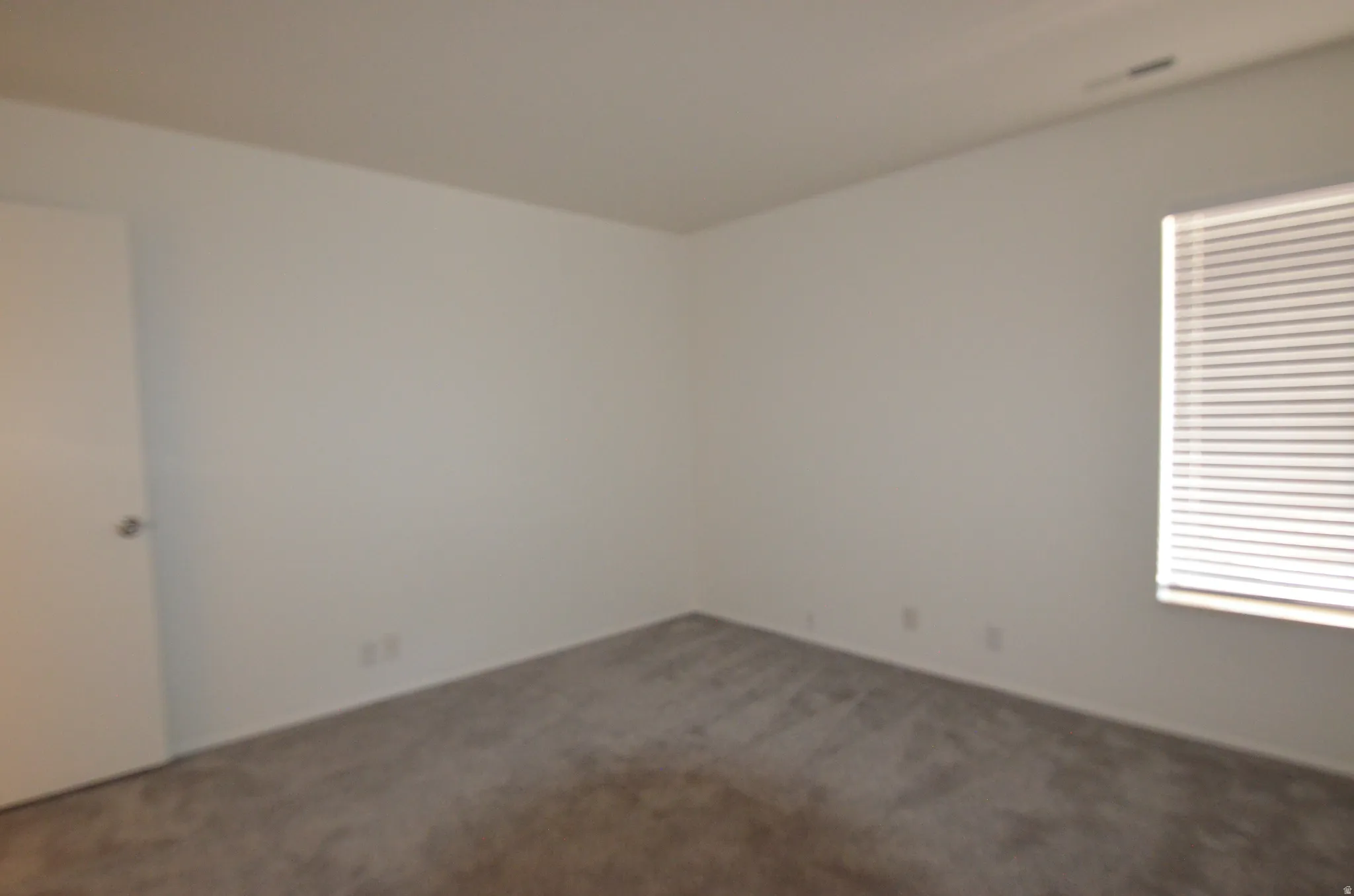 2nd view of 2nd bedroom with new carpeted room with neutral wall tones and white baseboards