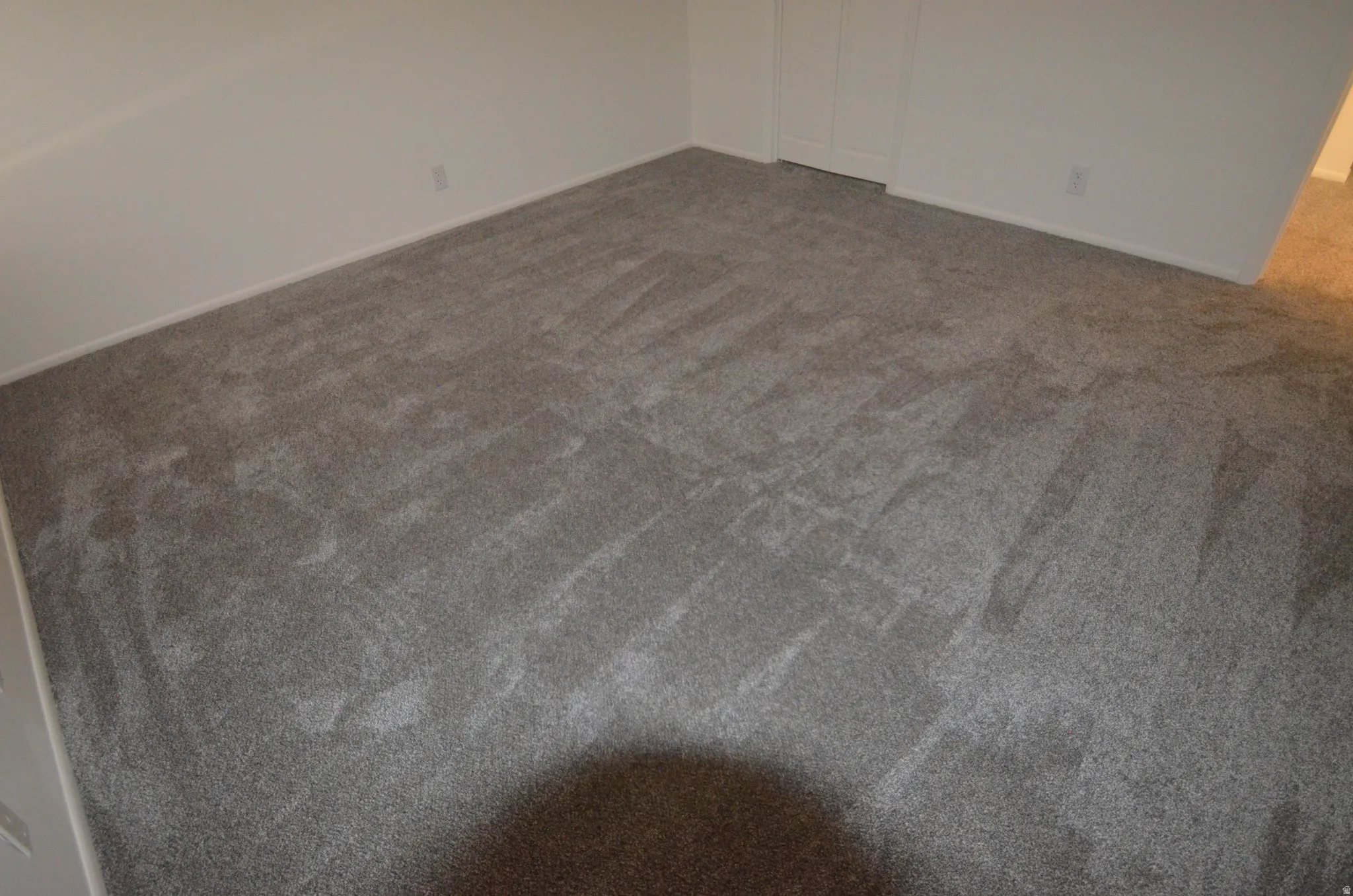 New grey carpeted flooring with white baseboards and neutral wall paint