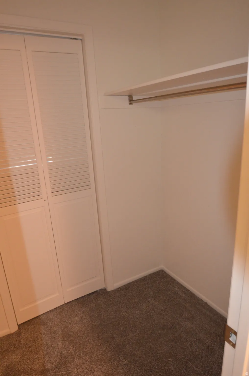 Closet interior featuring a hanging rod, upper shelf, and bi-fold louvered doors
