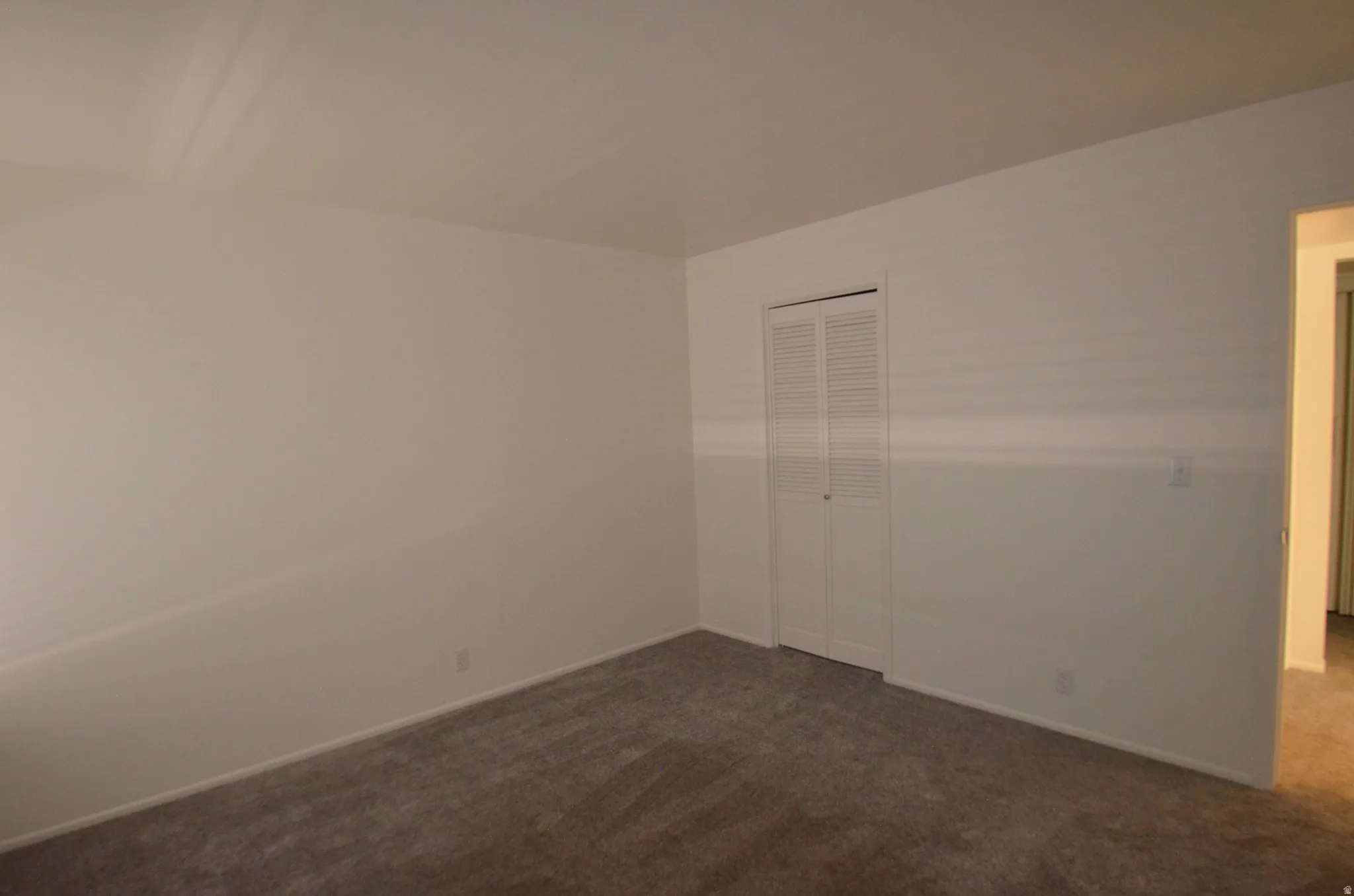 1st view of 2nd bedroom with new carpeted room with neutral wall tones and white baseboards