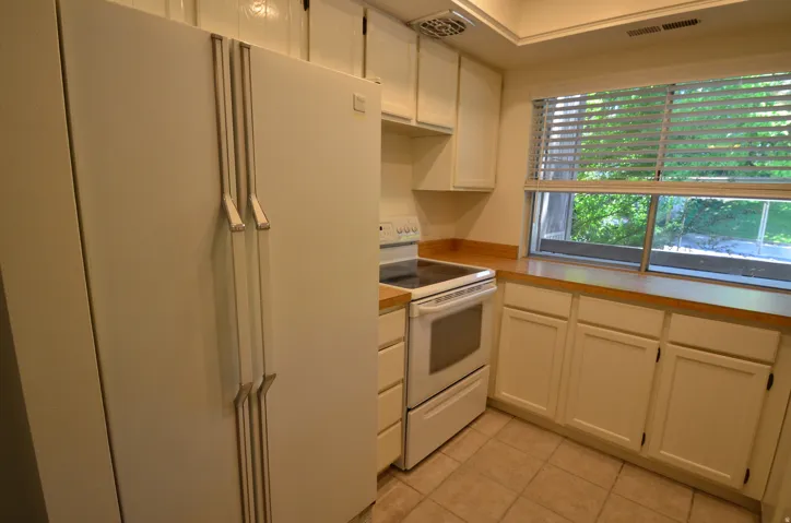 Kitchen featuring white cabinetry, wood-finish countertops, white electric range, and a dual-door refrigerator