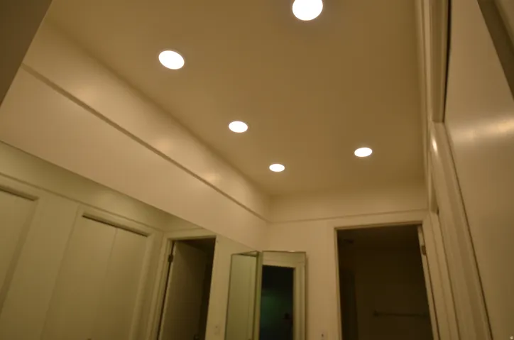 Main bedroom recessed ceiling lighting illuminates the space, featuring a full-width wall mirror and white painted walls