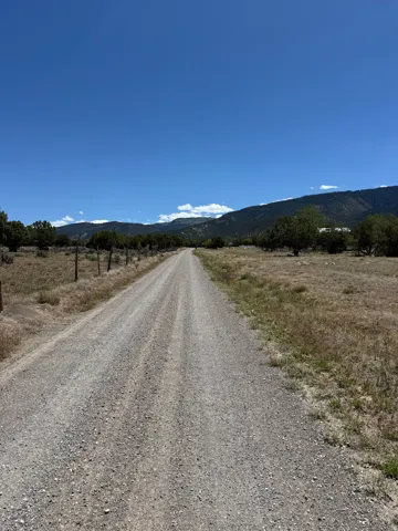 Gravel road extending into the distance, bordered by fences and natural vegetation
