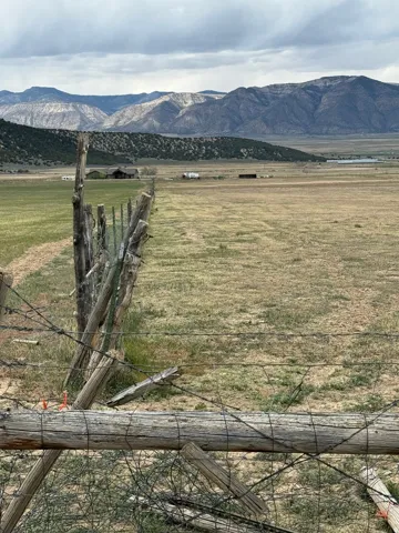 Expansive open field with distant mountain ranges and a visible wooden fence line