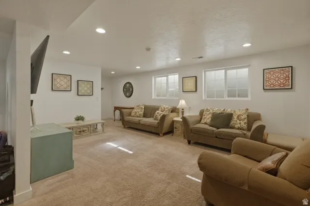 Spacious living area featuring recessed lighting, light-toned carpeting, and multiple windows