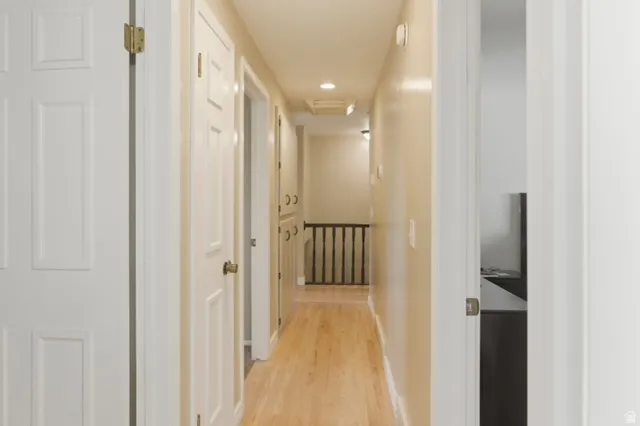 Hallway with wood-finish flooring, paneled doors, recessed lighting, and built-in cabinetry