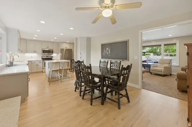 Spacious kitchen and dining area featuring light wood-finish flooring, recessed lighting, and a ceiling fan