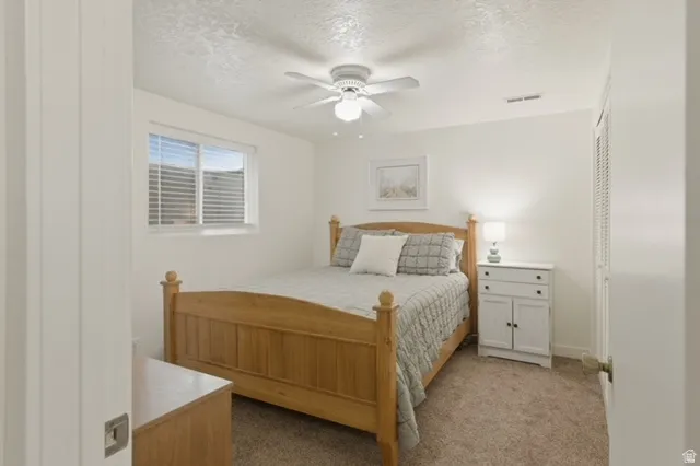 Carpeted room with a ceiling fan, a window with horizontal blinds, and a built-in accordion-door closet
