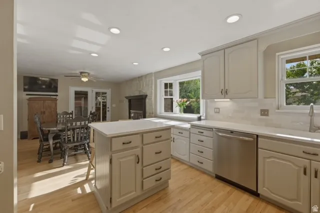 Bright kitchen featuring light wood-finish flooring, white cabinetry, solid surface countertops, and a subway tile backsplash