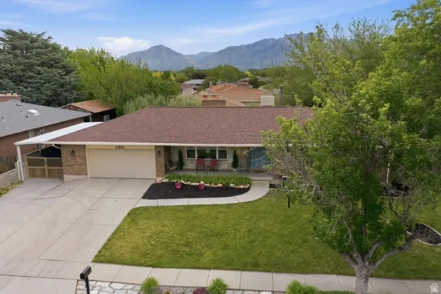 Ranch-style residence featuring a brick facade, attached garage, and a covered carport