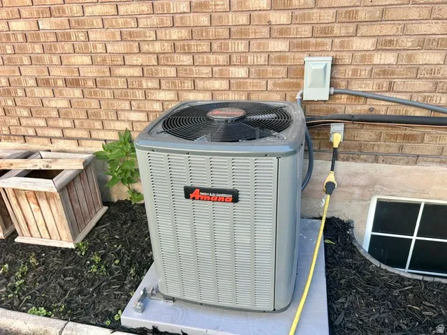 Central air conditioning unit on a concrete pad with brick exterior