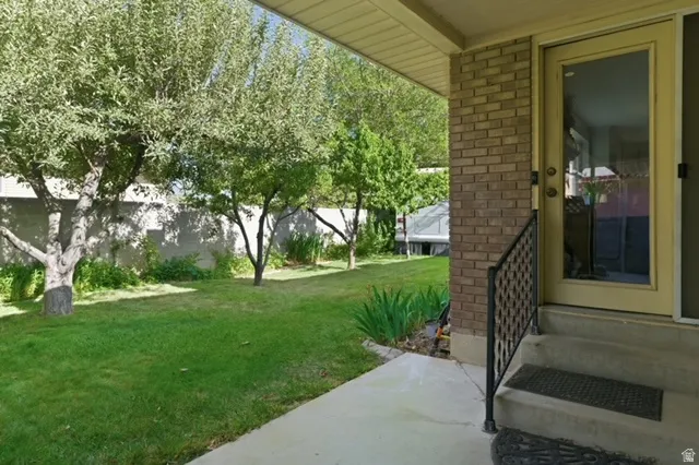 Covered patio area with concrete flooring, framed by a brick wall and a glass-paneled exterior door