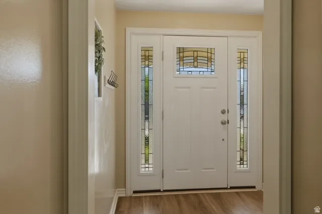 Entryway featuring a white paneled door with decorative glass, flanked by two sidelight windows with matching glasswork