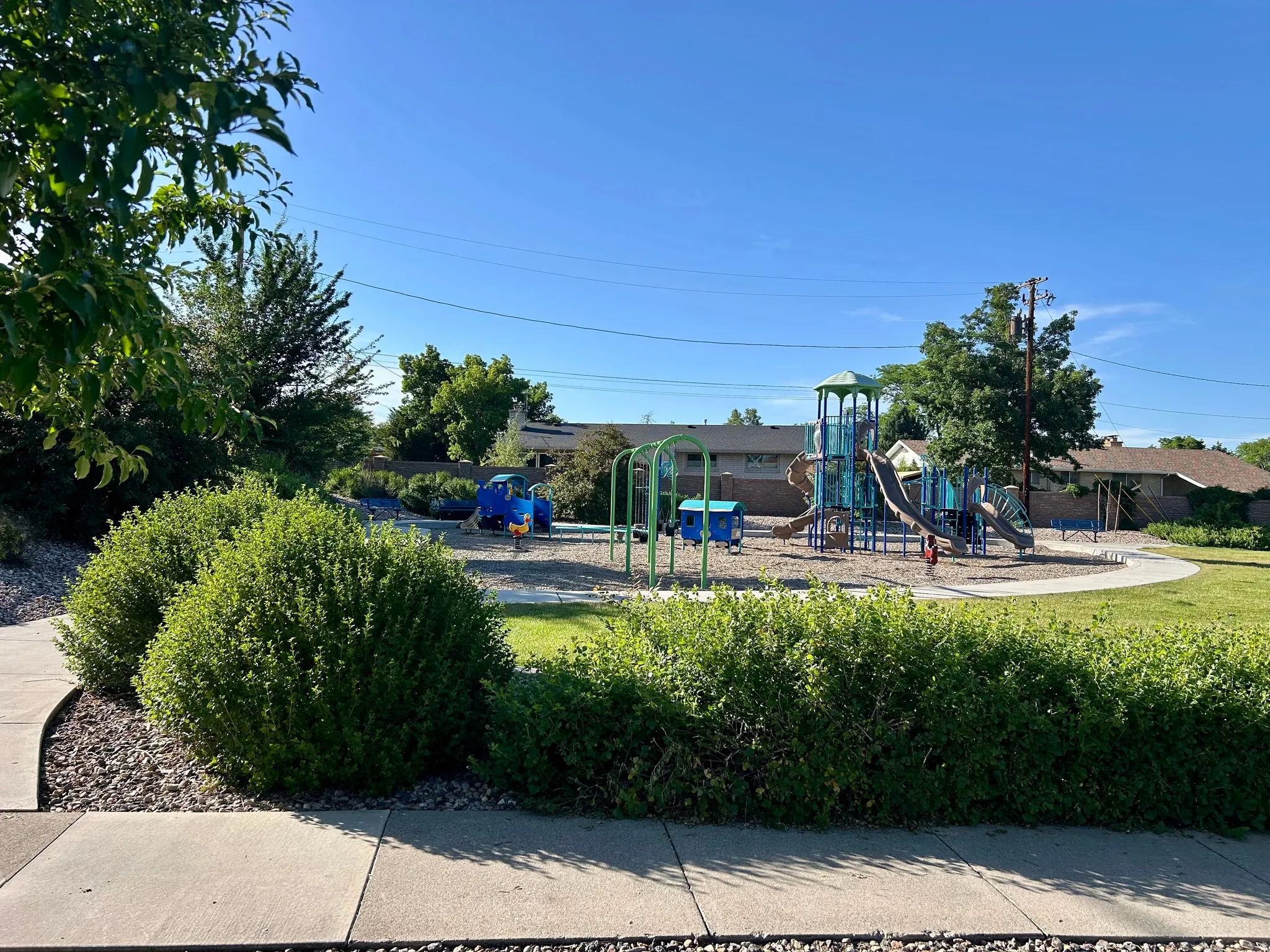 Community playground featuring multiple play structures, slides, swings, and a circular walking path