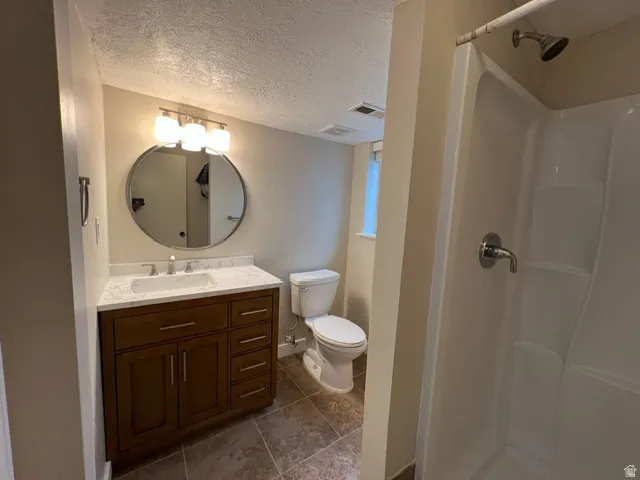 Bathroom featuring a wood-tone vanity with a white countertop, an undermount sink, and a round wall-mounted mirror