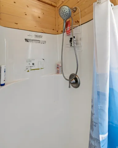 White fiberglass shower surround with a handheld shower fixture