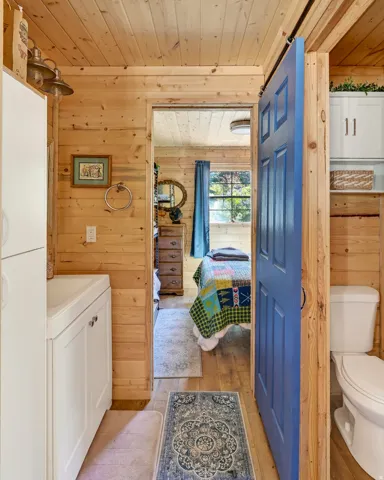 Wood-paneled interior featuring a white vanity with integrated sink, a cobalt blue barn door, and a white toilet