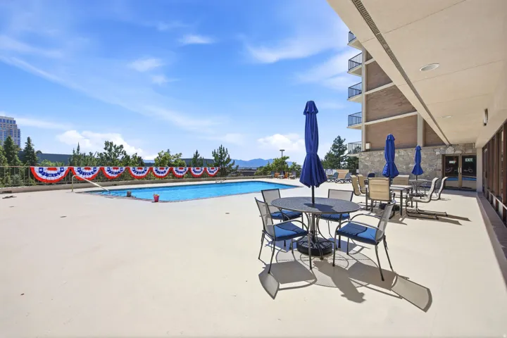 Expansive outdoor patio featuring an inground swimming pool, concrete decking, and multiple seating areas with tables and umbrellas