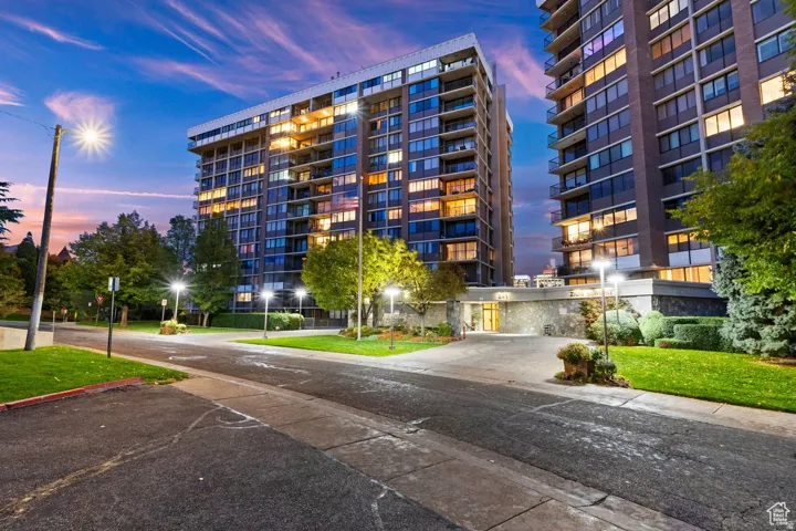 Modern high-rise residential building featuring extensive glazing, private balconies, and a stone-clad entry
