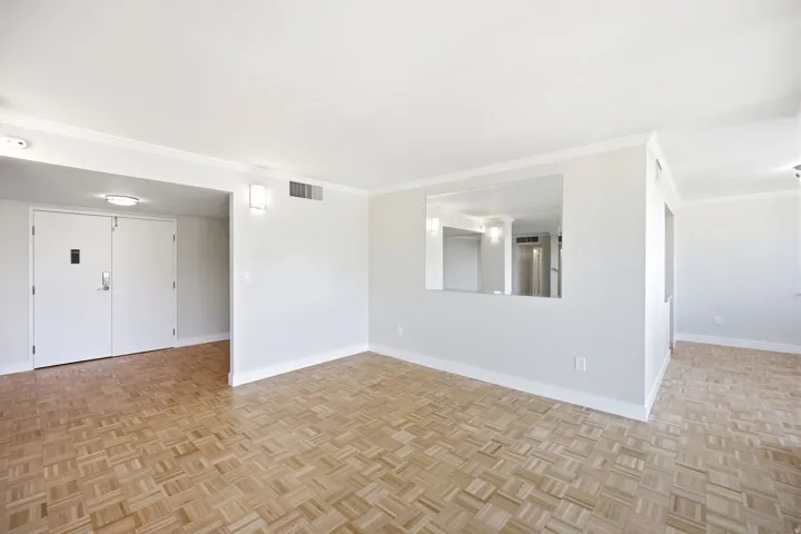 Living area featuring parquet wood-finish flooring, white baseboards, and crown molding