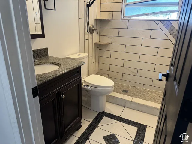 Bathroom featuring a dark wood vanity with a granite countertop, undermount sink, and dark-framed mirror