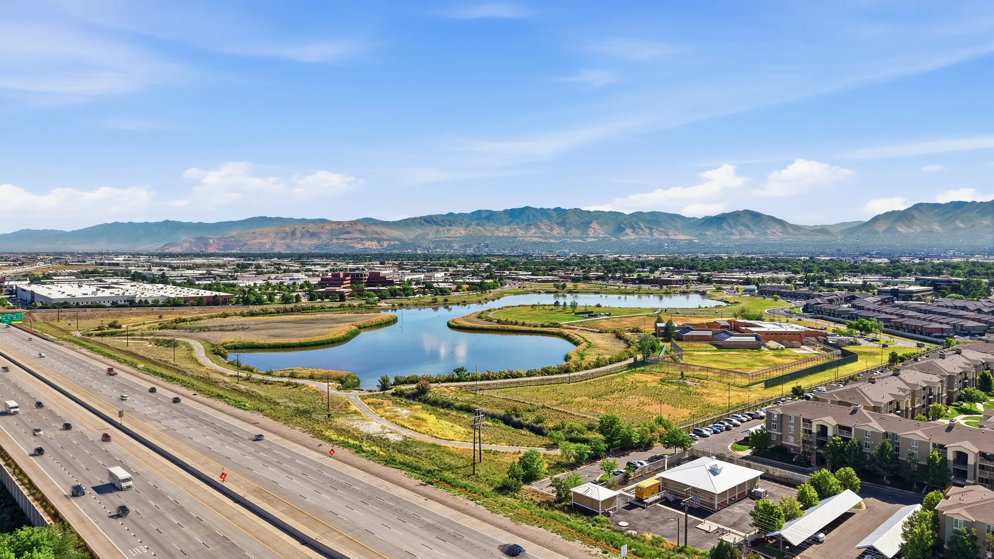 Expansive aerial perspective showcasing a multi-lane highway, a natural water feature, and distant mountain ranges