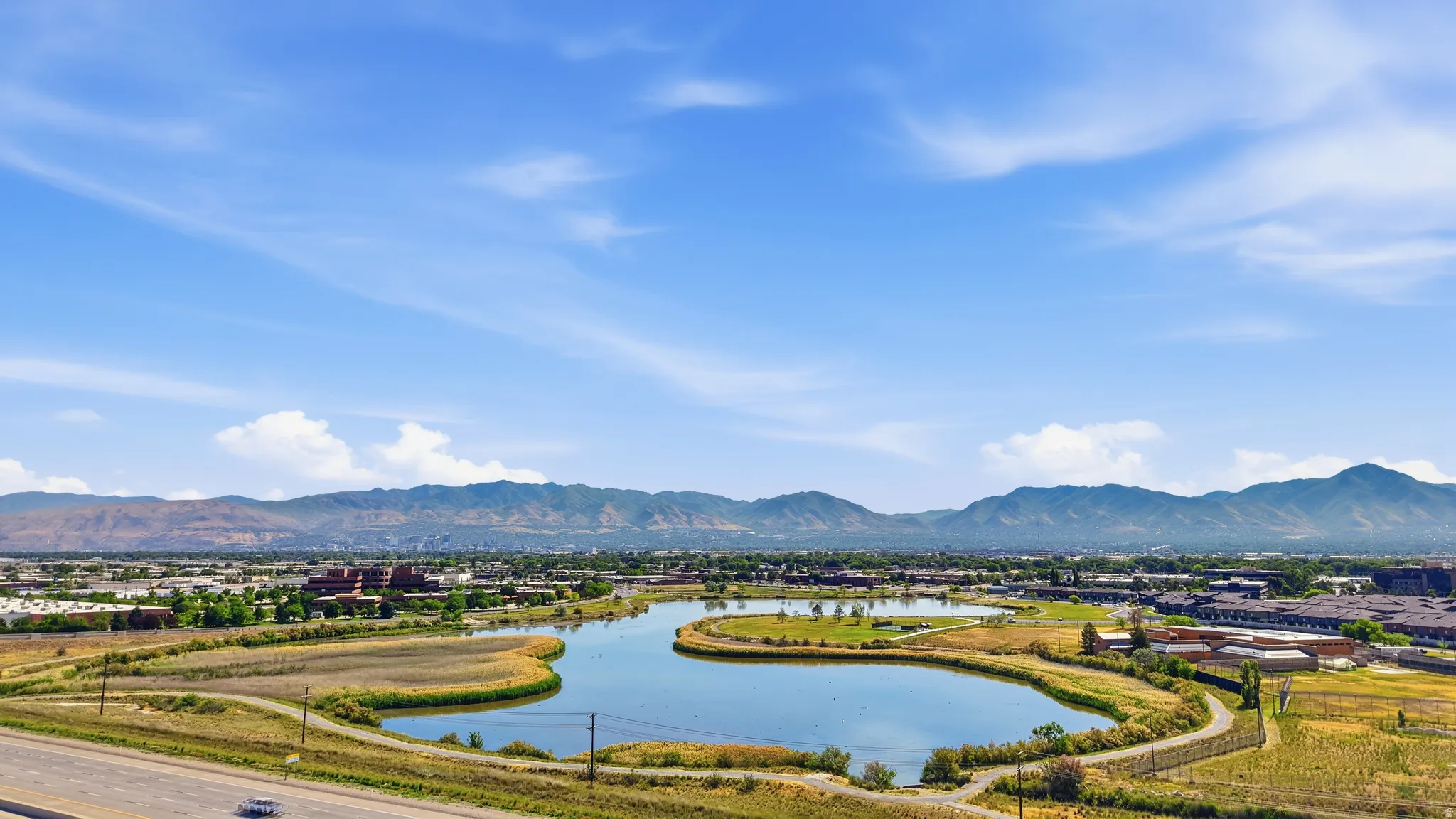 Expansive water feature with surrounding green spaces, set against a backdrop of distant mountains