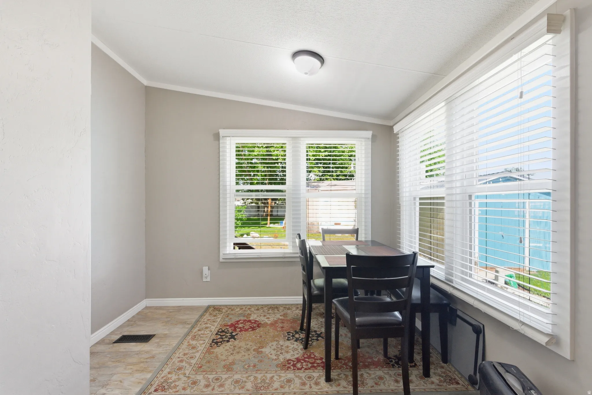 Dining area featuring multiple windows with blinds, tile flooring, and a ceiling-mounted light fixture