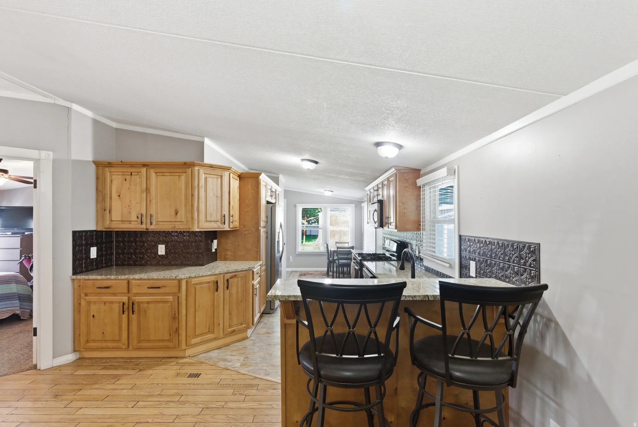 Spacious kitchen featuring wood cabinetry, light-toned countertops, and a decorative tile backsplash