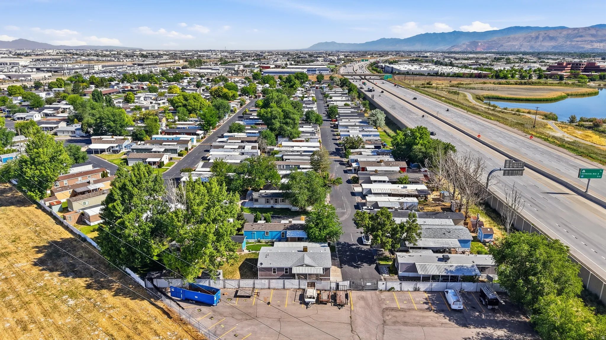 Aerial perspective showcasing a community layout with residential structures, mature trees, paved roads, and a large parking area