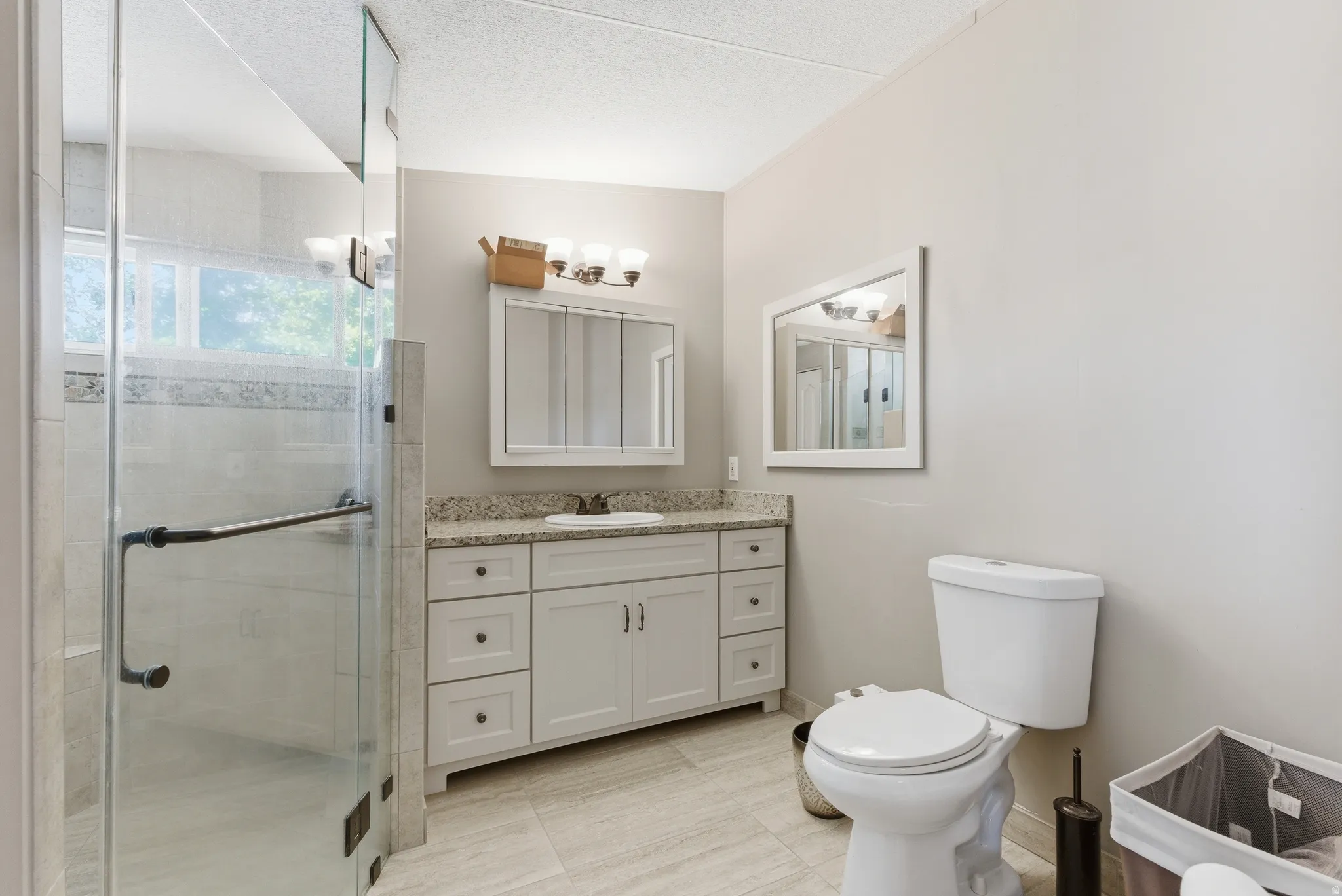 Bathroom featuring a glass-enclosed shower, light-toned wall tile, and a decorative horizontal accent tile
