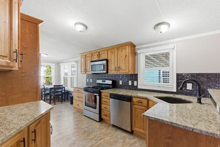 Kitchen featuring wood cabinetry, granite-finish countertops, and a black patterned backsplash