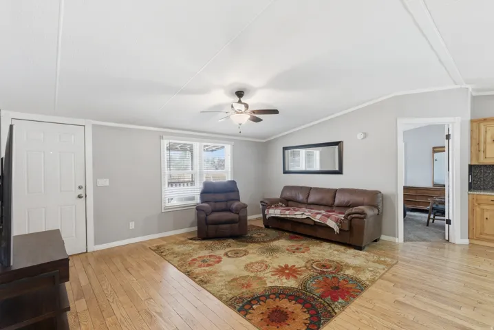 Open concept living area featuring wood-finish flooring, light gray wall paint, and a ceiling fan