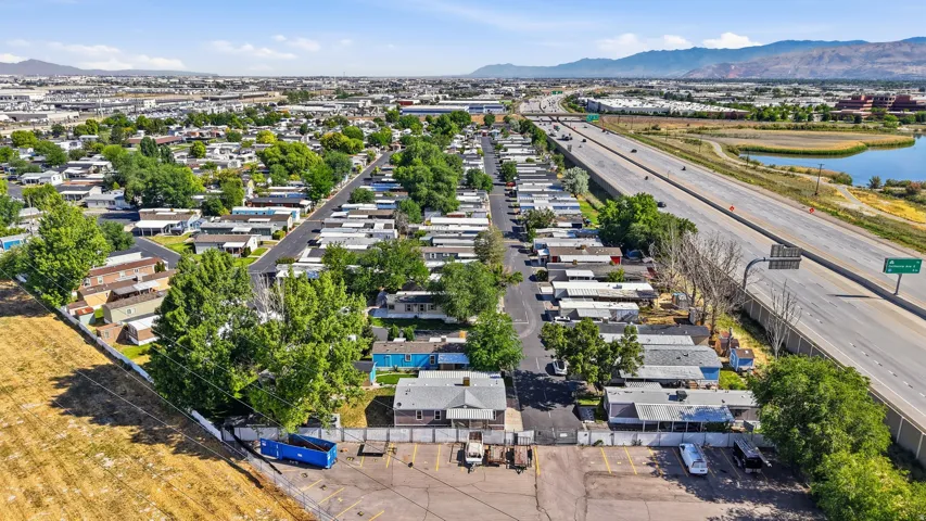 Aerial perspective showcasing a community layout with residential structures, mature trees, paved roads, and a large parking area