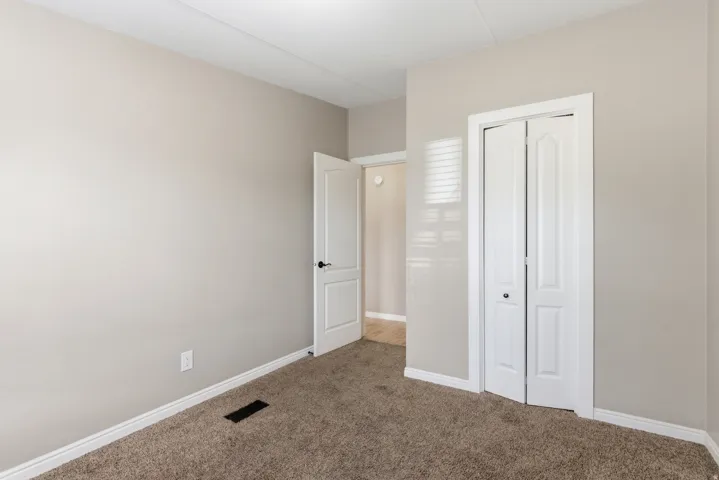 Carpeted room with neutral wall tones and white baseboards