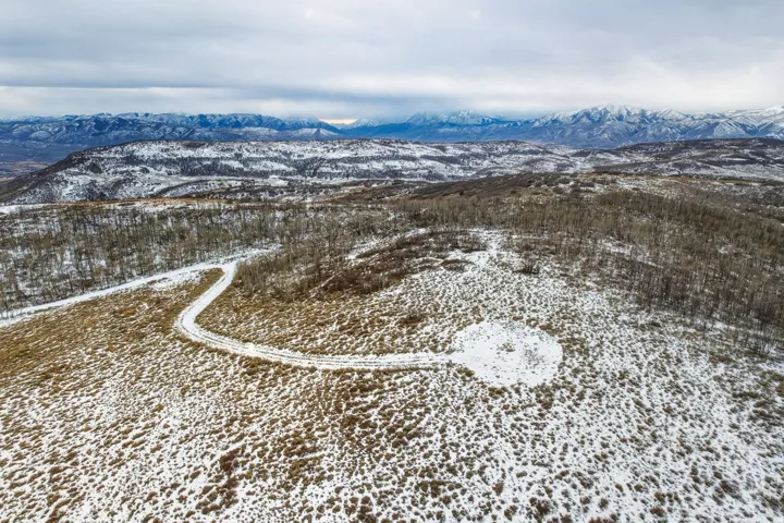Expansive, snow-dusted landscape featuring a winding access road