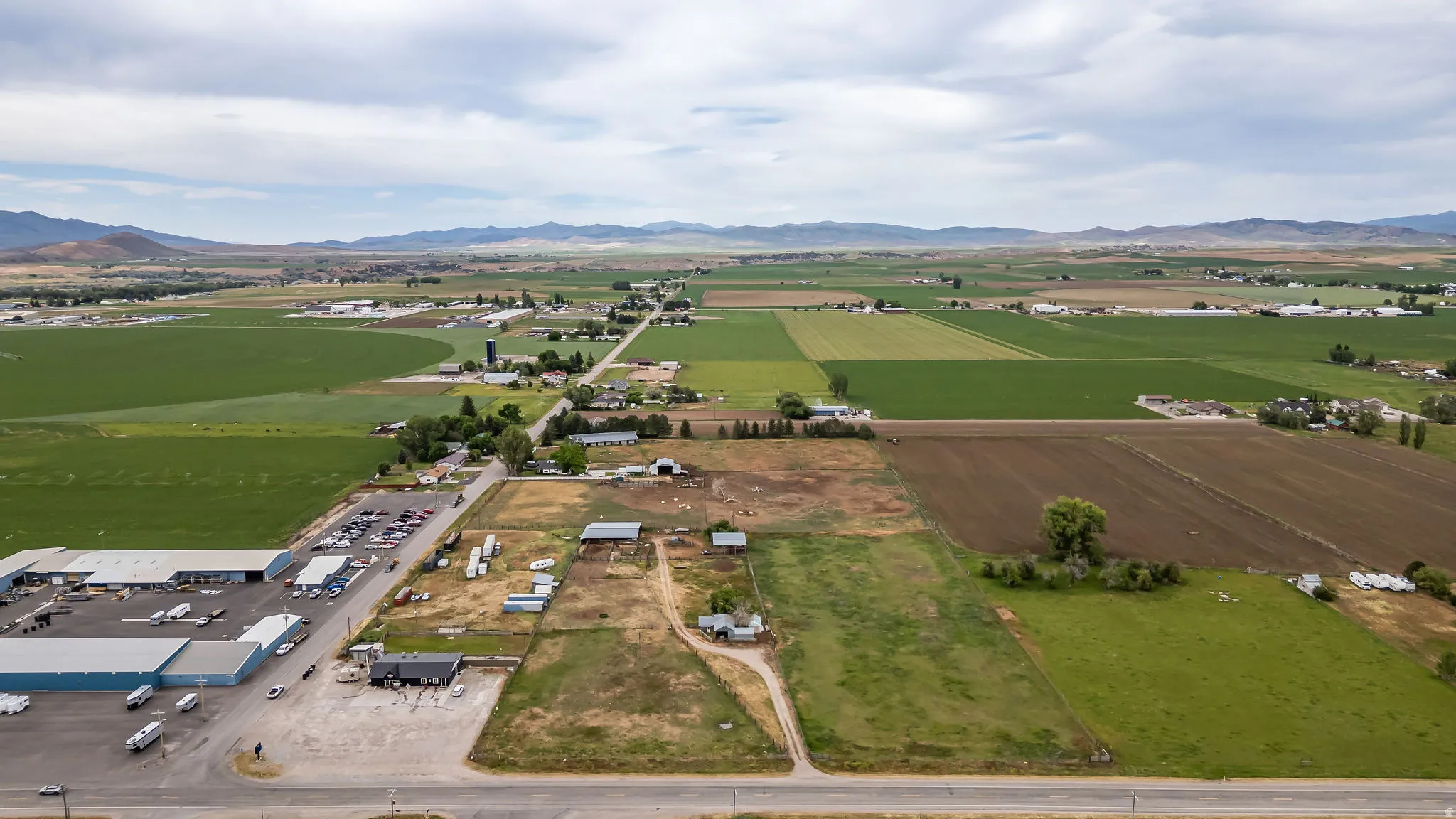 Expansive agricultural landscape featuring varied green fields, cultivated land, and distant mountains