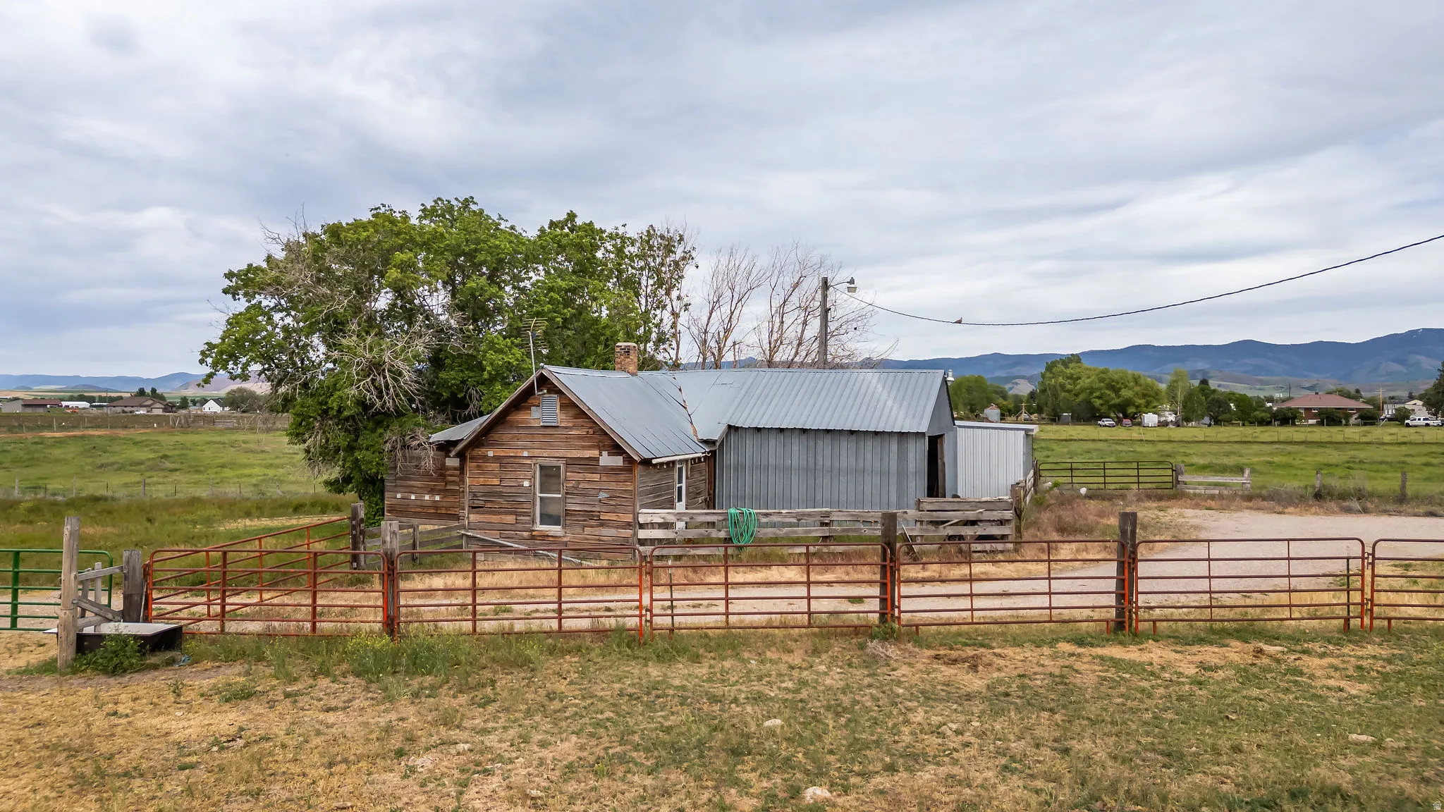 Rustic wood-sided dwelling with a metal roof, accompanied by a corrugated metal outbuilding